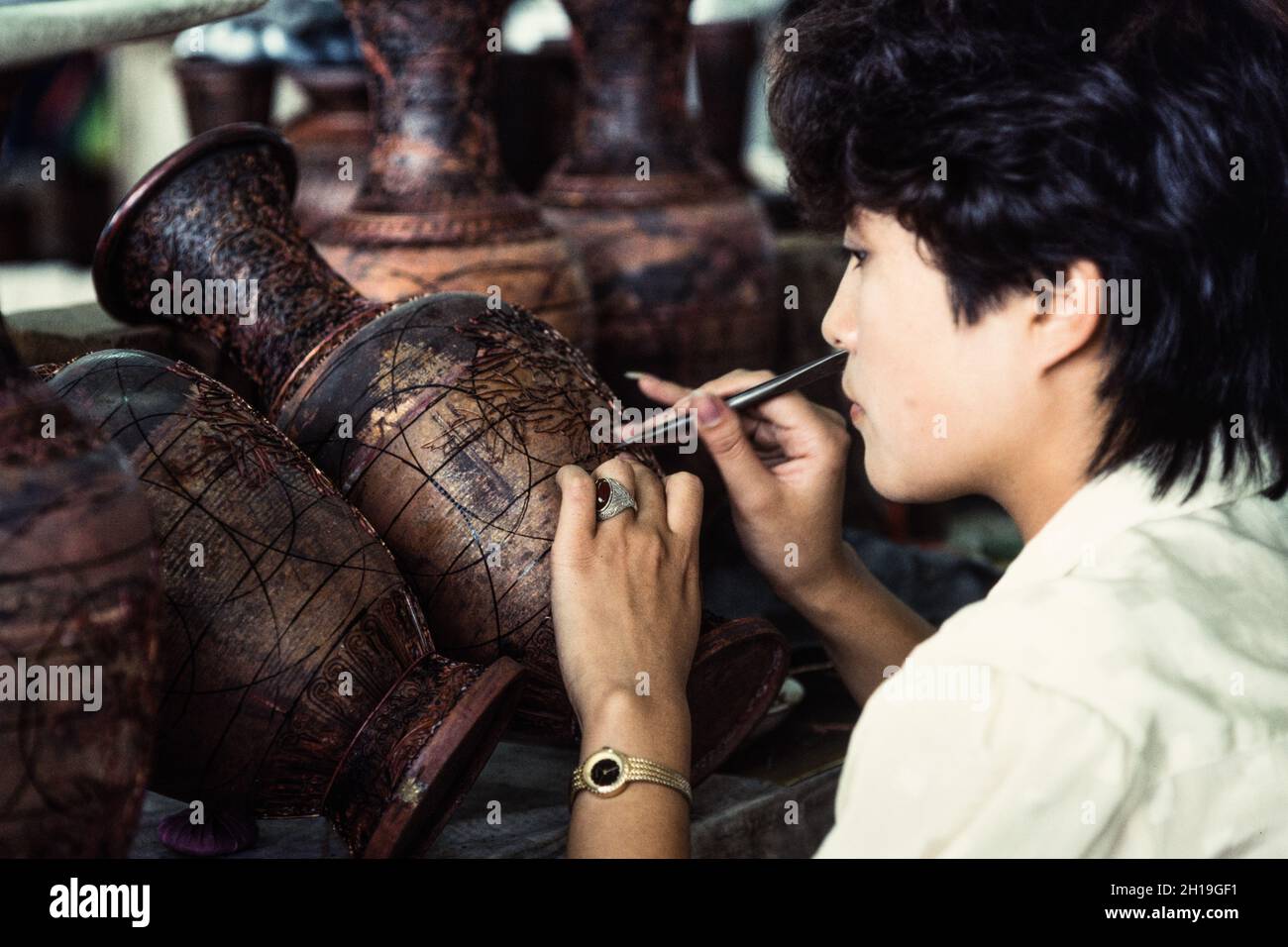 An artisan attaches cloisons or wire strip to make the design for a cloissone vase in a workshop in Beijing, China. Stock Photo