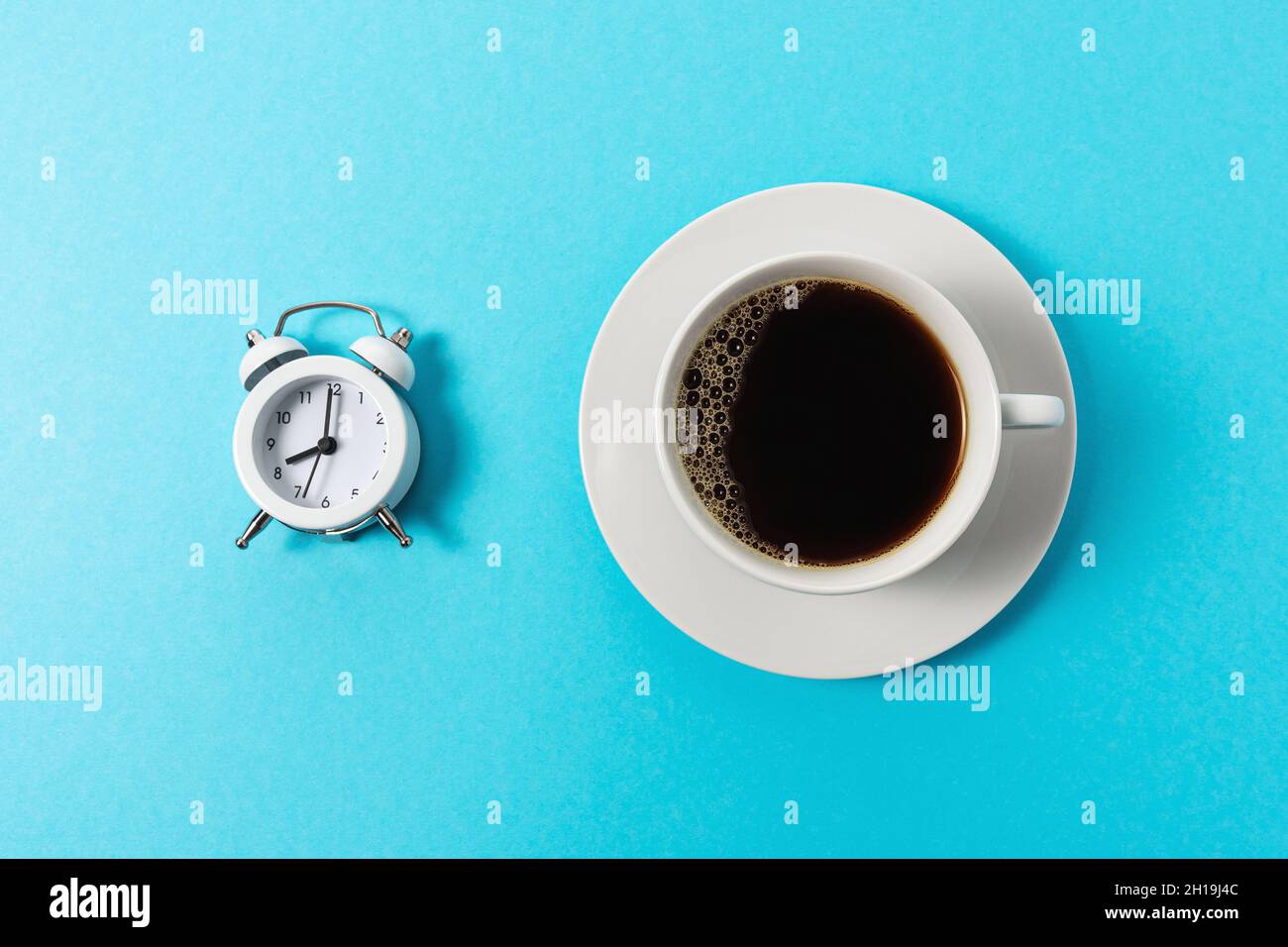 Creative layout made with cup of coffee and alarm clock on blue ...