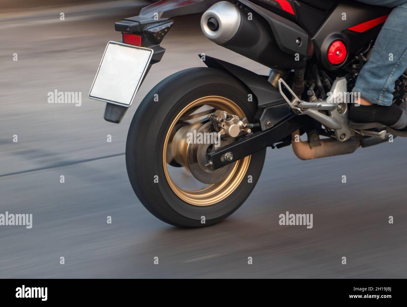 The rear wheel of a motorcycle driving on a motion blurred road Stock