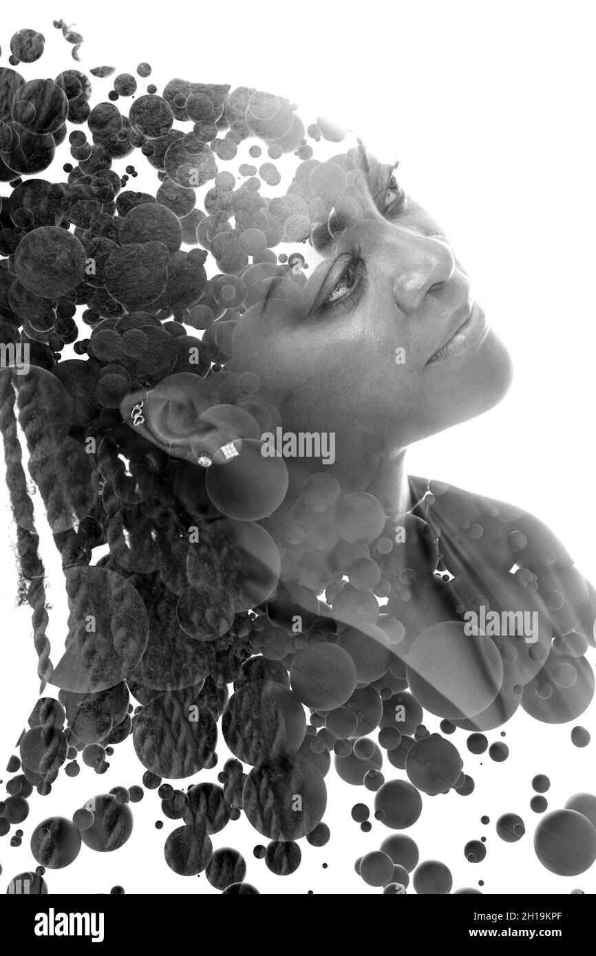 A black and white portrait of a woman combined with floating black 3D spheres in a double exposure technique. Stock Photo