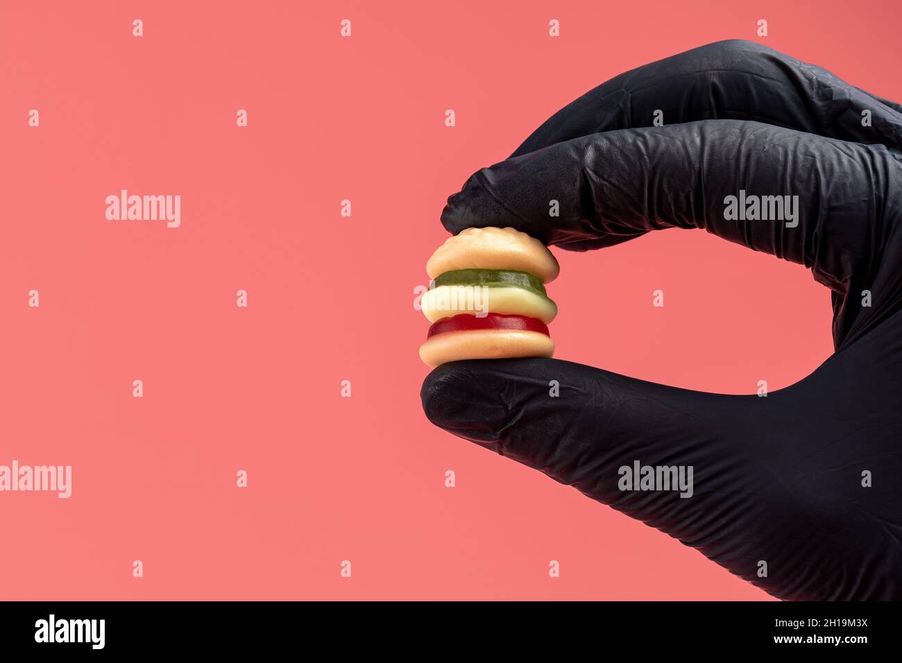 Colorful candy hamburger with a hand in black glove. Minimal food concept. Stock Photo