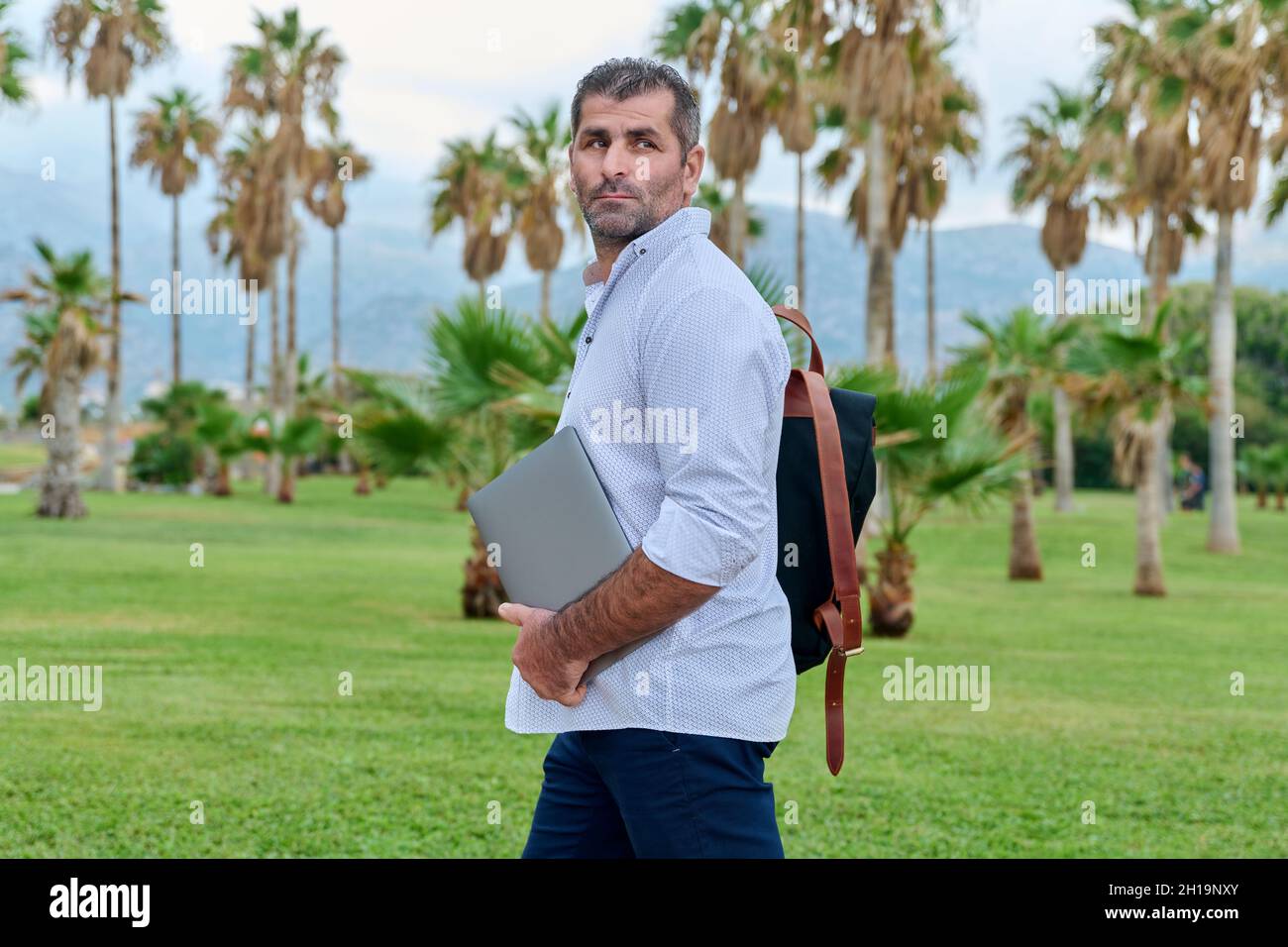 Portrait of serious confident mature man with laptop outdoors Stock Photo