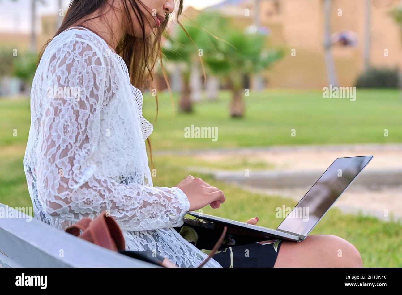 Young beautiful woman outdoors with laptop, tropical park background Stock Photo