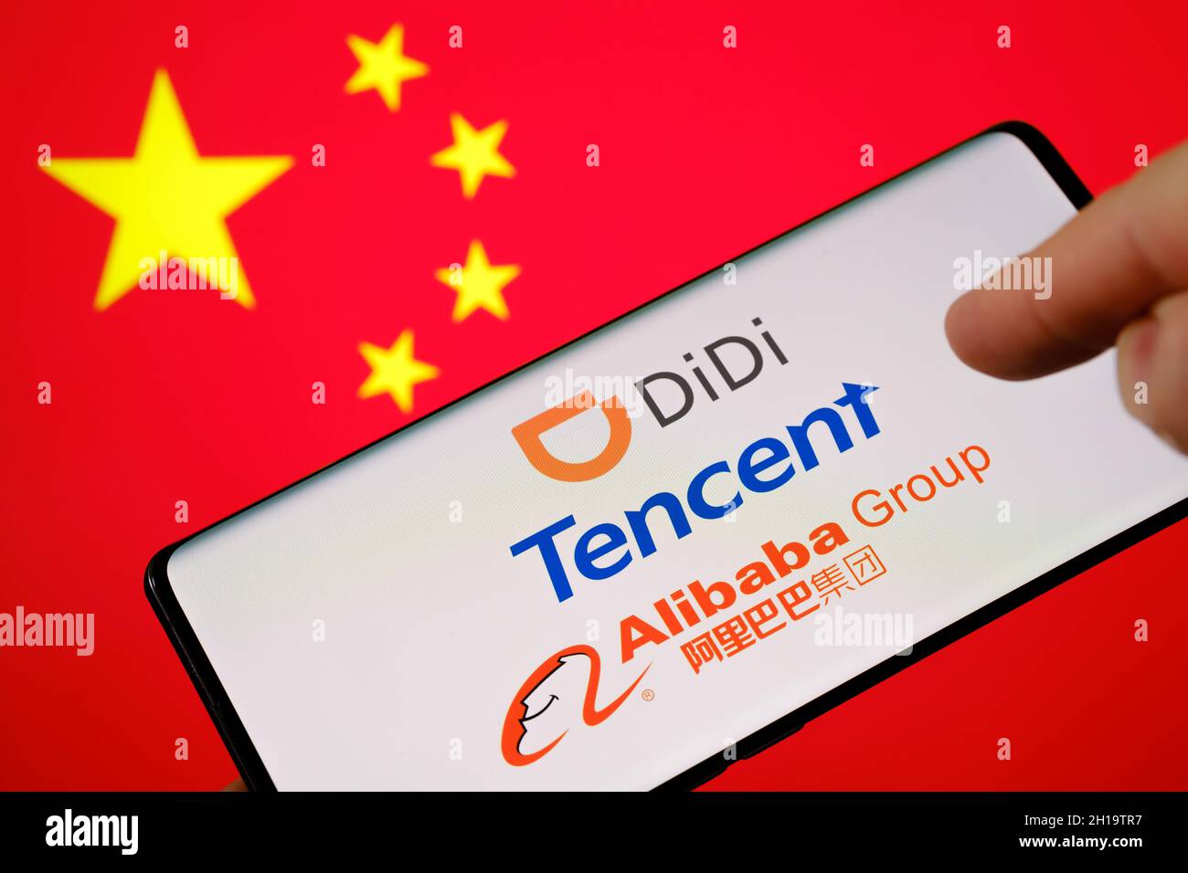 Chinese BigTech concept. DiDi, Tencent, Alibaba logos seen on smartphone and blurred flag of China on the background. Stafford, United Kingdom, Octobe Stock Photo