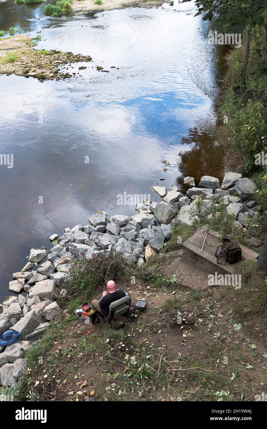dh Fishing RIVER WHARFE YORKSHIRE Angler man sitting on riverbank with rod uk Stock Photo