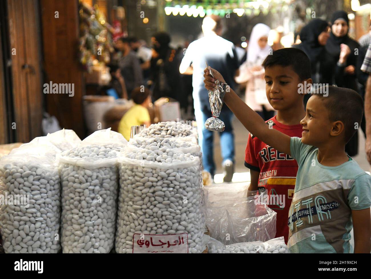 Damascus, Syria. 17th Oct, 2021. Children buy sugared almonds at a market on the occasion of the birthday of Prophet Muhammad in Damascus, Syria, on Oct. 17, 2021. Credit: Ammar Safarjalani/Xinhua/Alamy Live News Stock Photo