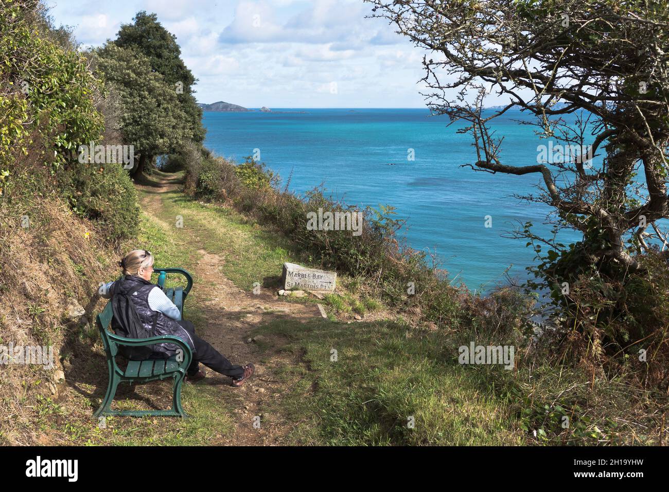 dh Footpath ST MARTIN GUERNSEY Woman sitting on Saint Martins cliff path bench people Stock Photo