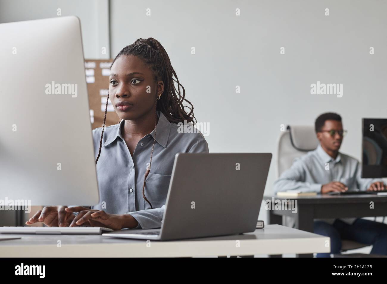 Portrait of two African-American young people using computers while working in software development office, copy space Stock Photo