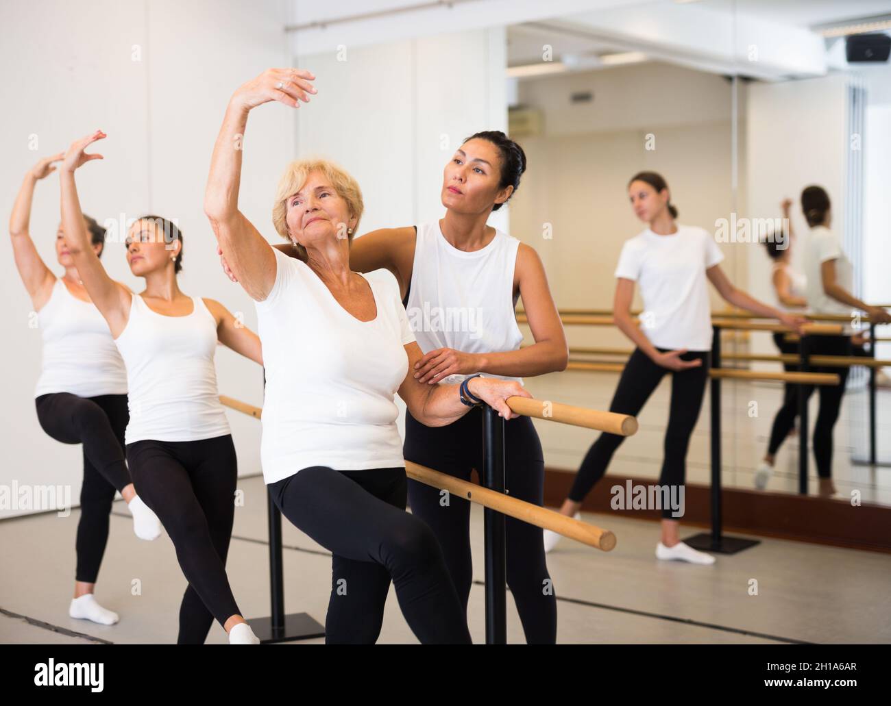 Various aged women exercising ballet moves with trainer Stock Photo