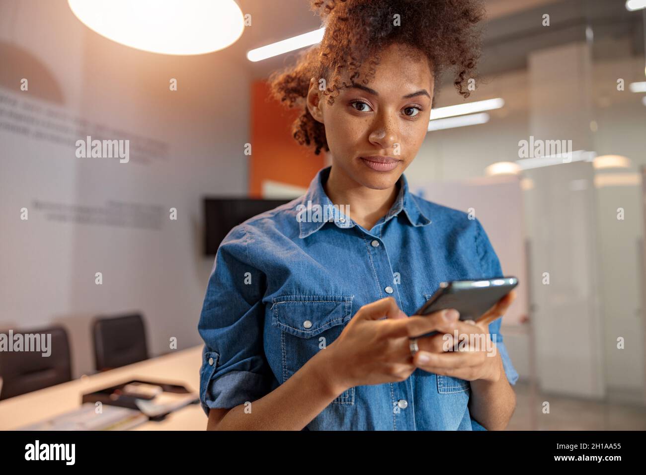Multiethnic female employer holding smartphone in hands Stock Photo