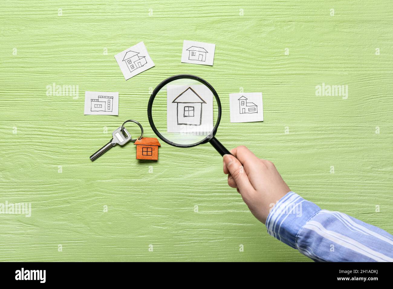 Magnifying Key Female hand holding magnifier, key with keychain and drawings of houses ...