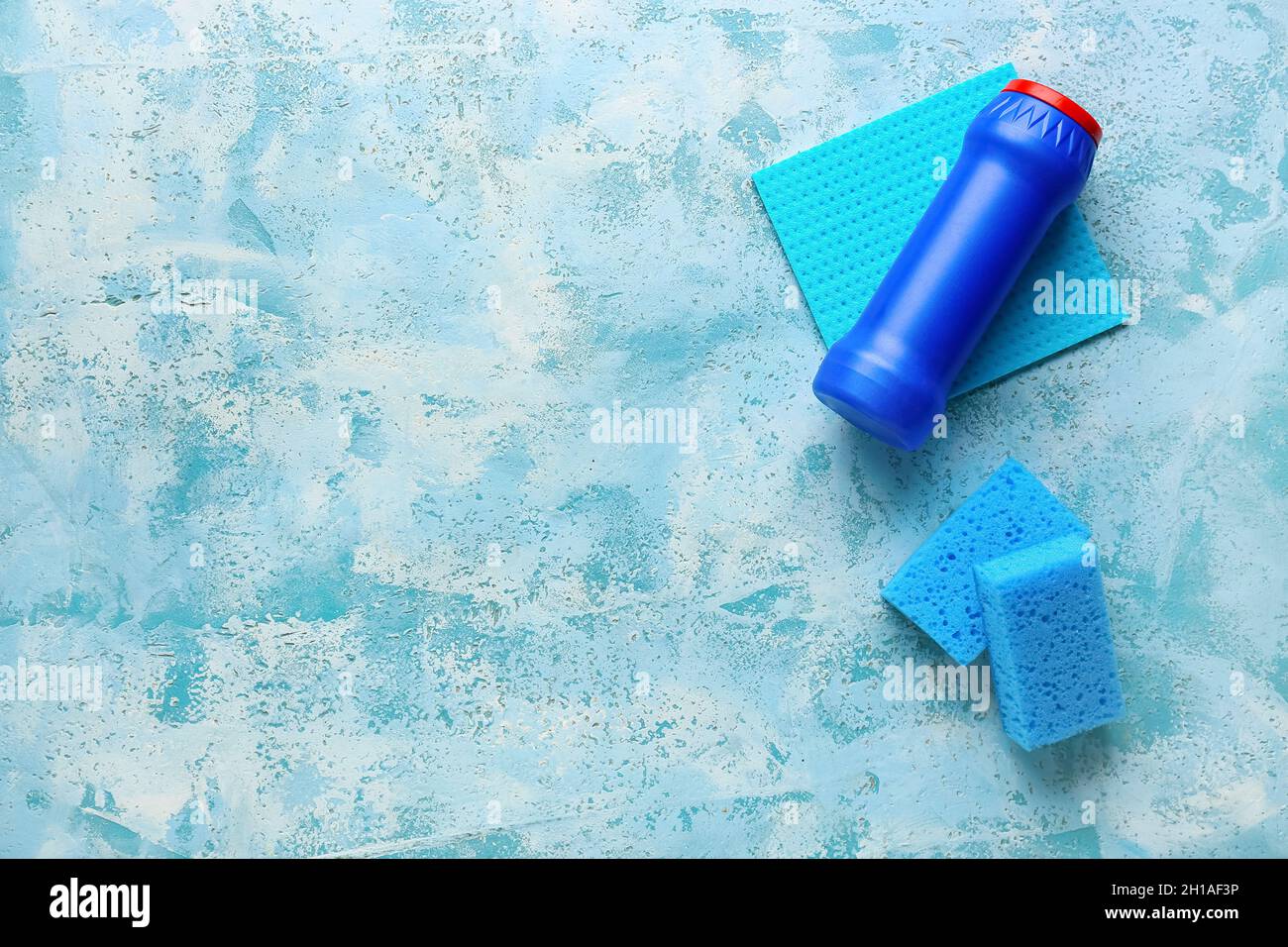 Blue cleaning sponges, rag and bottle of detergent on grunge color ...