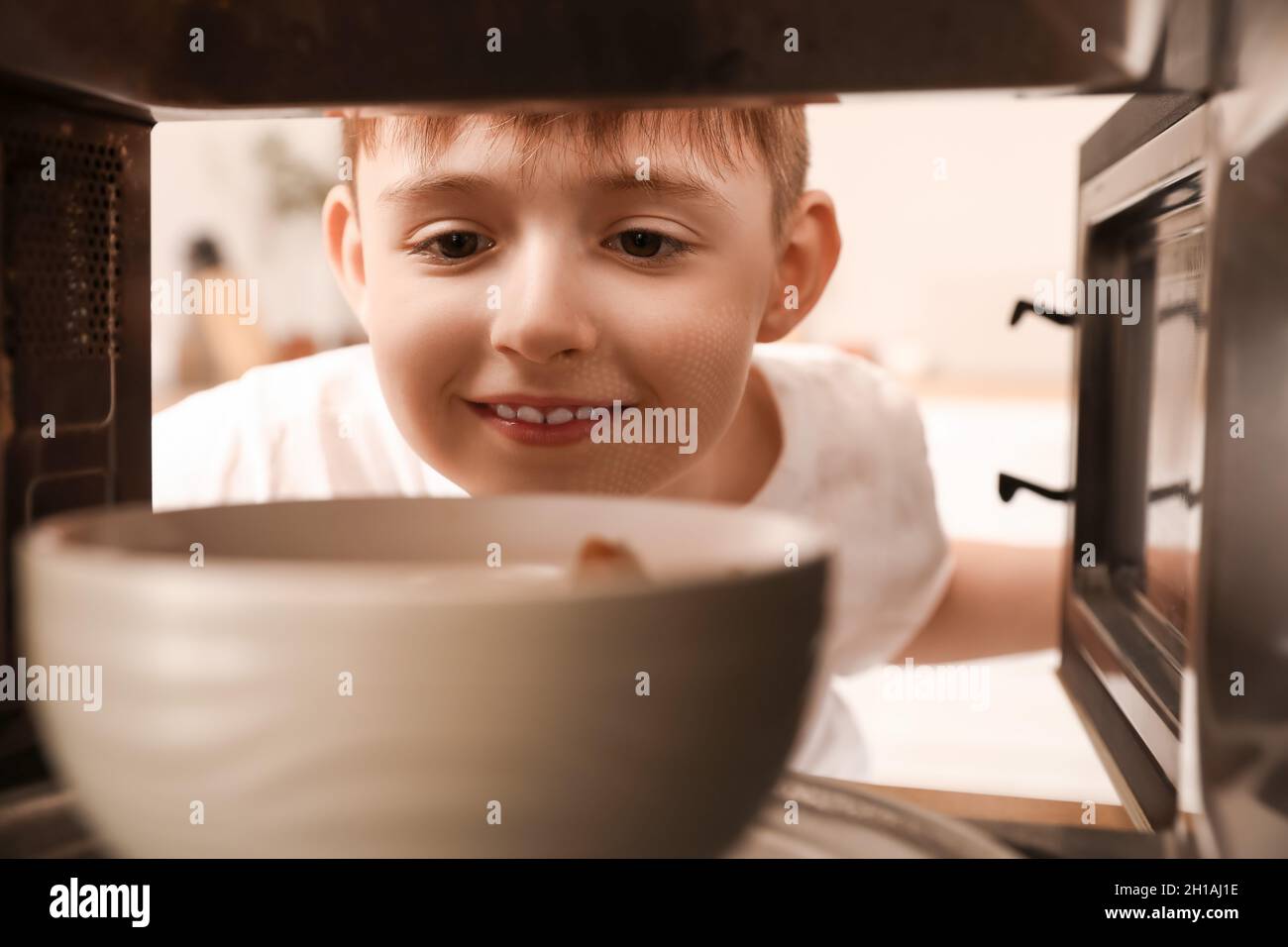 Little boy heating food in microwave oven, view from inside Stock Photo
