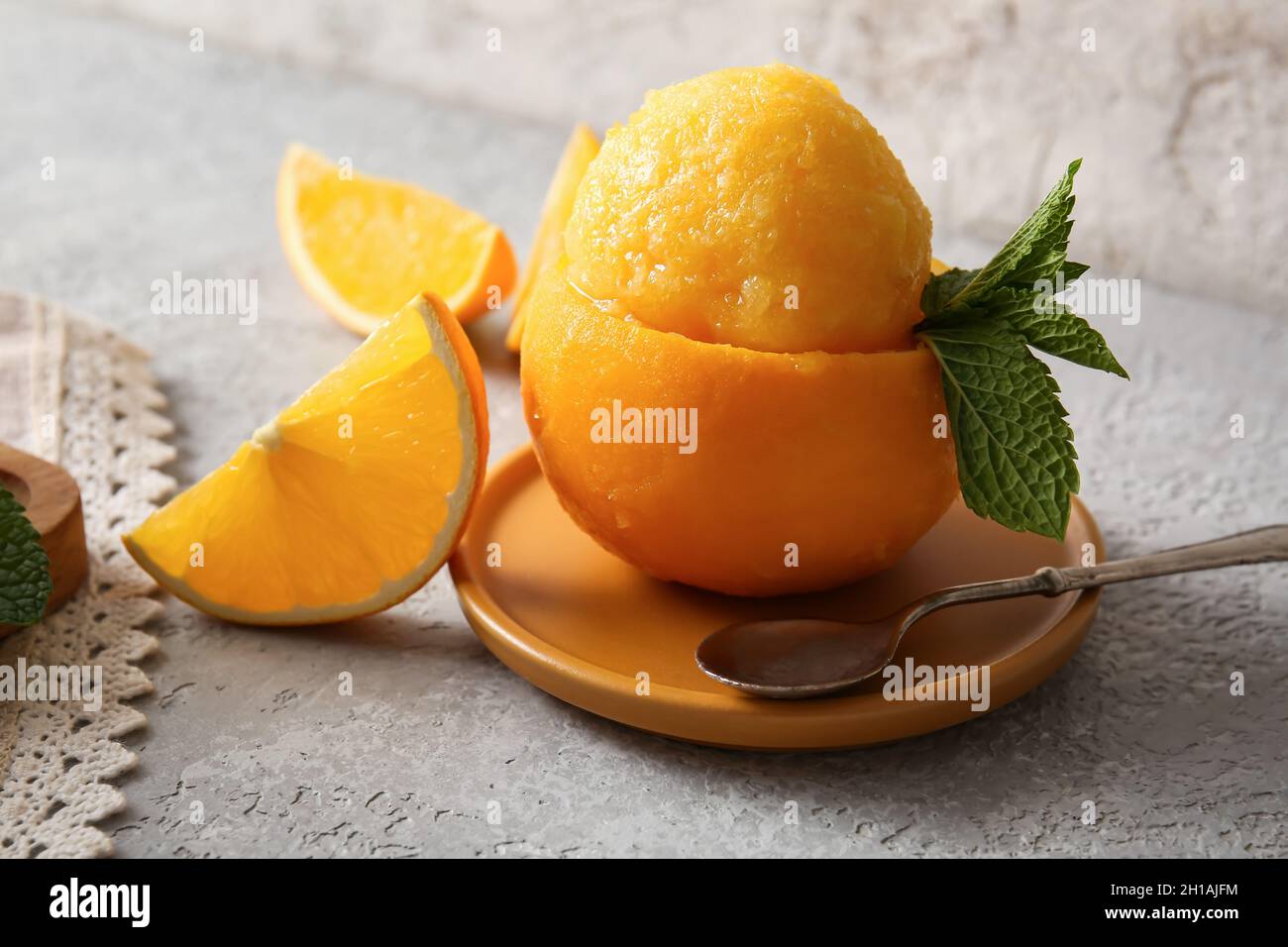 Board with tasty ice cream in orange peel on grey background Stock
