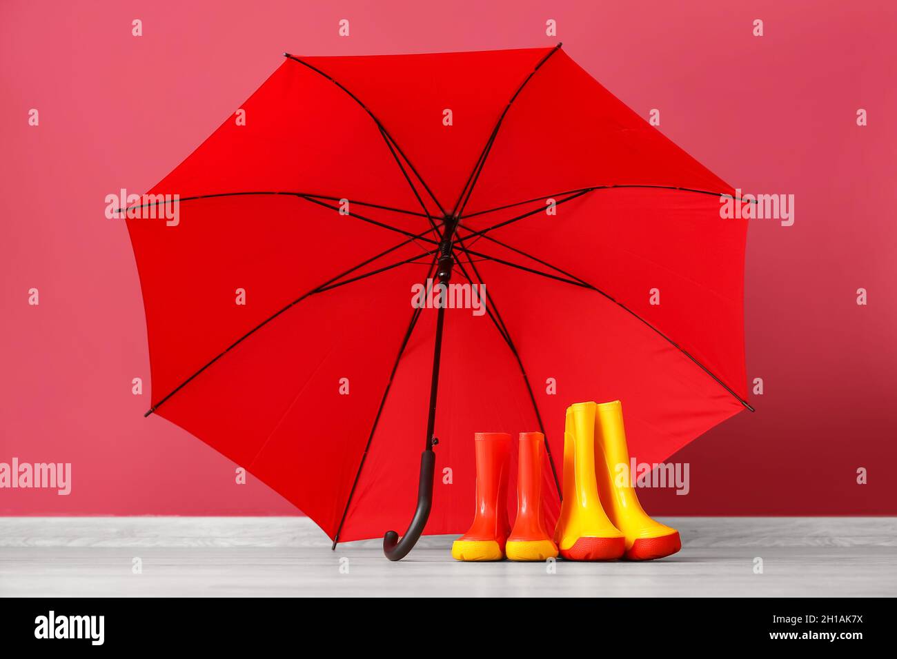 Rubber rain boots and umbrella on floor near color wall Stock Photo Alamy