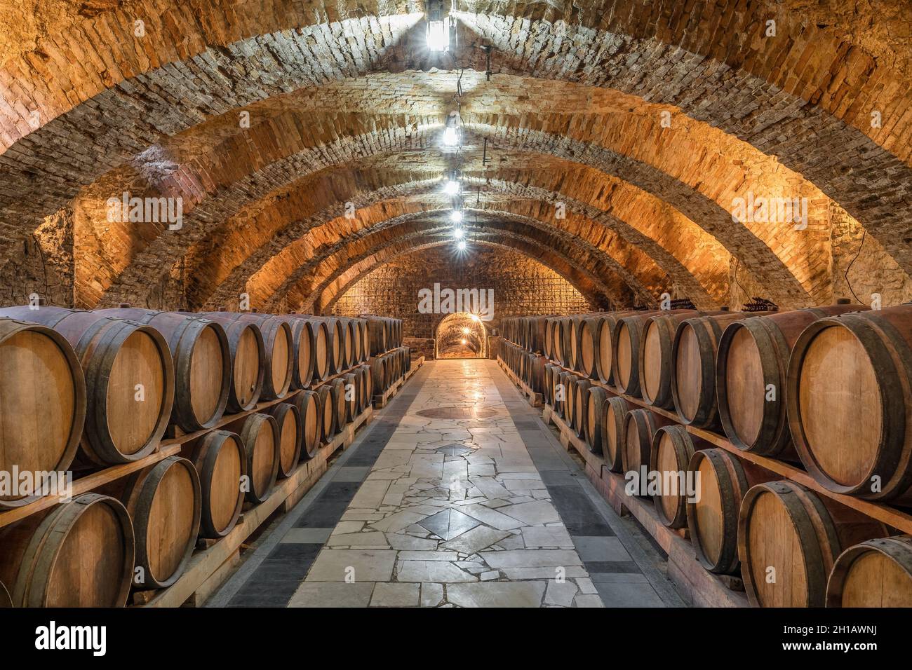 Old wooden barrels with wine in the ancient medieval cellars Stock Photo