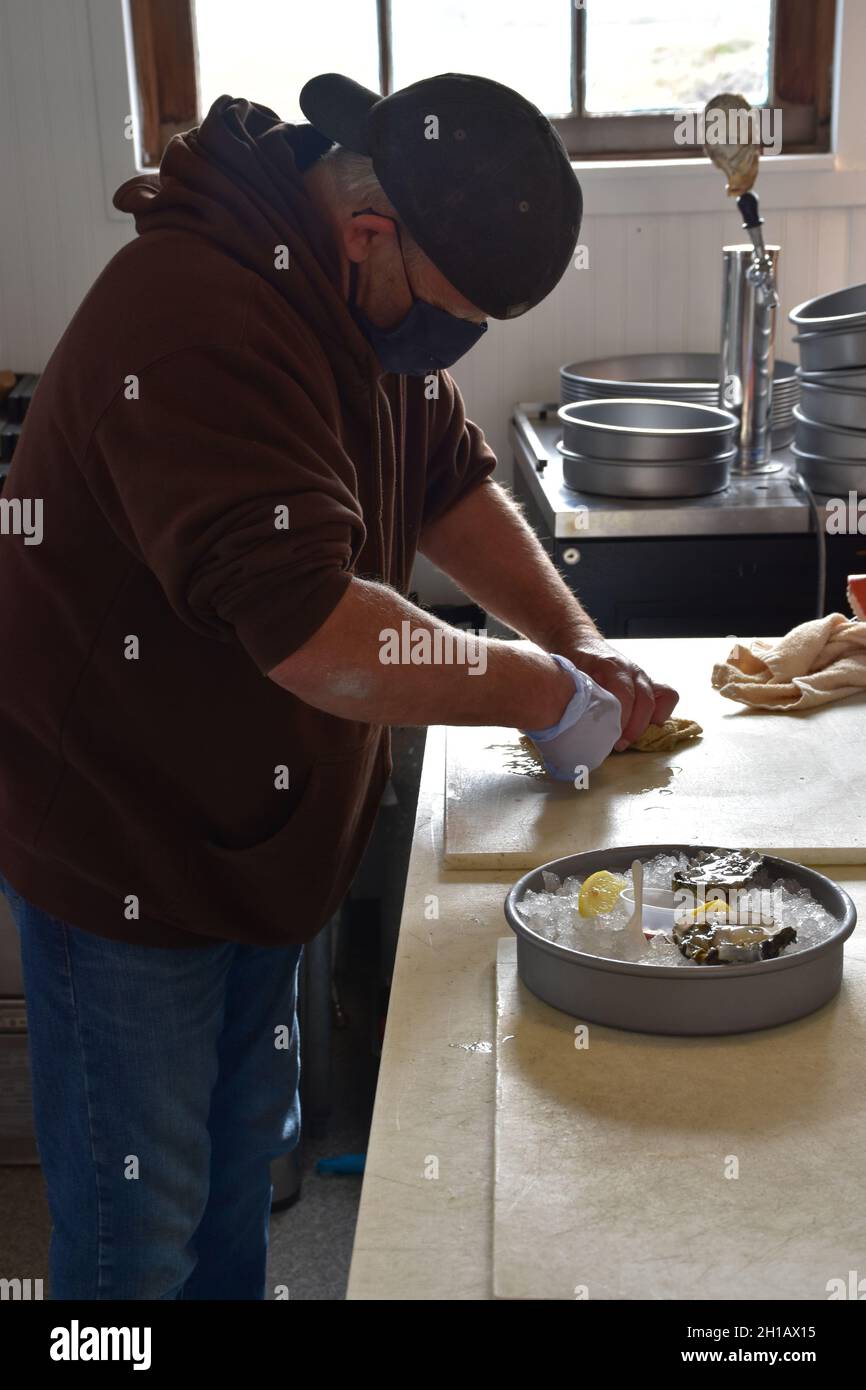 A male staff member shucks fresh oysters at Oysterville Sea Farms