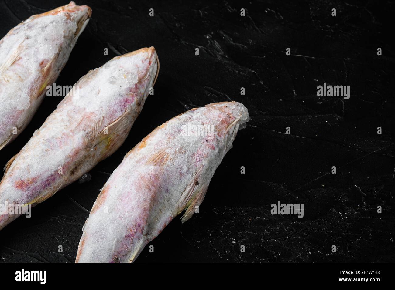 Frozen red mullet or barabulka raw fish set, on black dark stone table ...