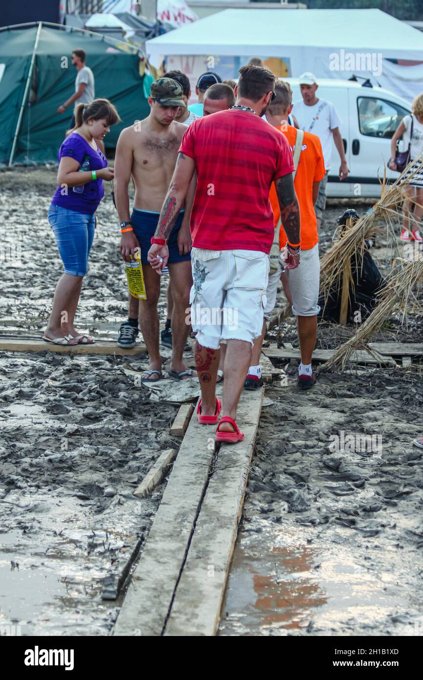 People walk on planks that are lying in the mud. Bad weather during the