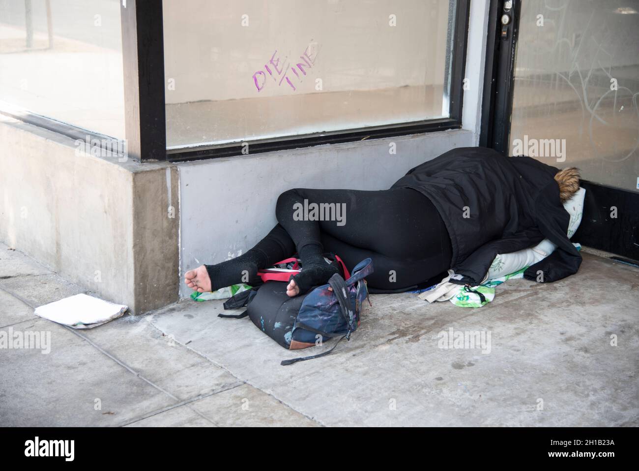 Los Angeles, CA USA July 12, 2021 Homeless woman sleeping in front of a vacant retail store