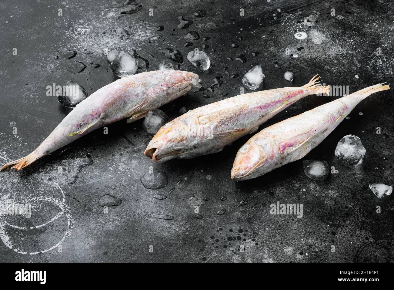 Frozen red mullet or barabulka raw fish set, on black dark stone table ...