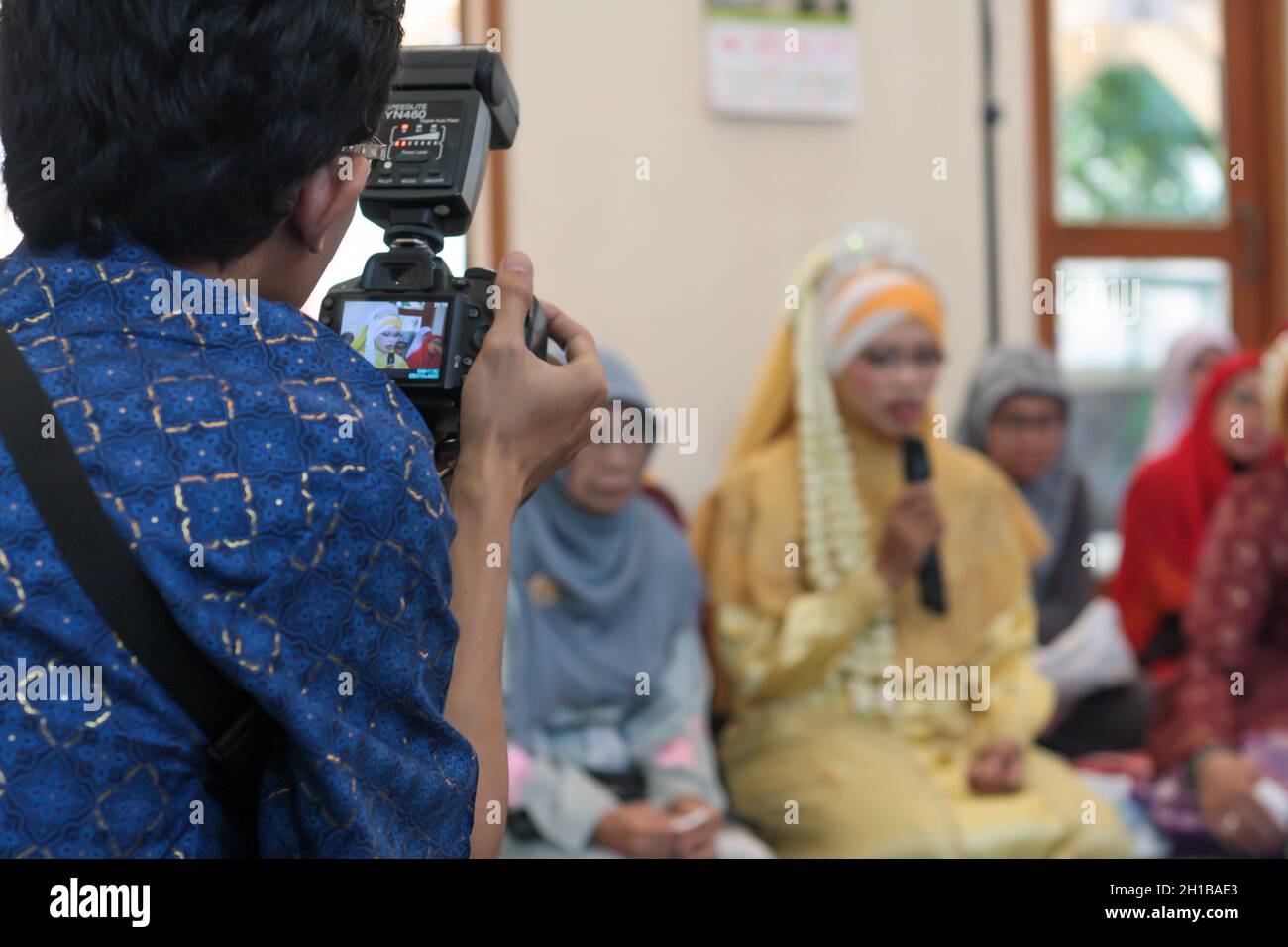 View of professional wedding photographer looking through viewfinder of digital camera composing before taking pictures in ceremony. Stock Photo