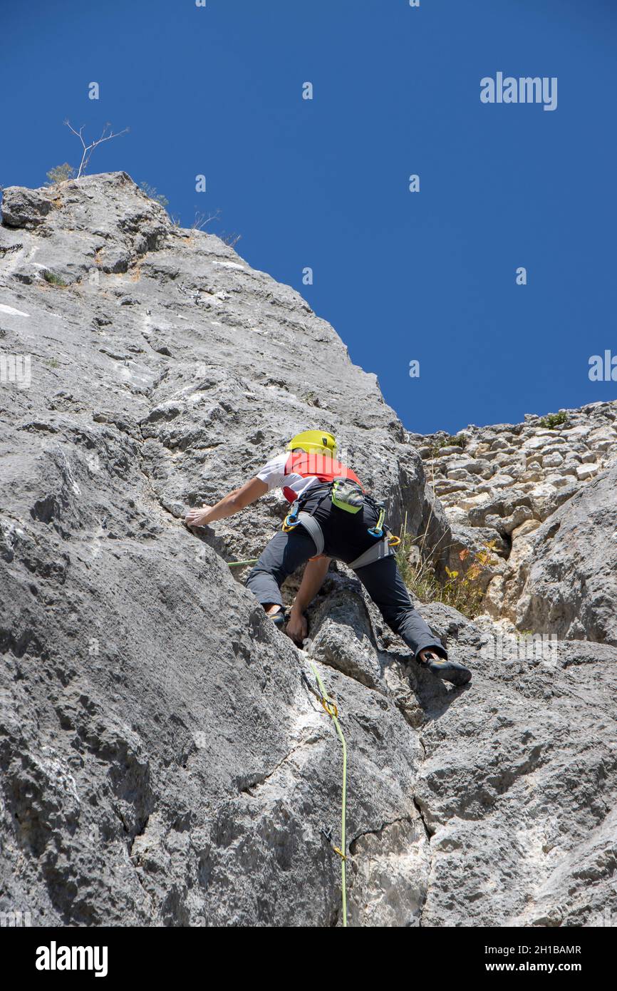 Young man climbing natural high rocky wall Stock Photo - Alamy