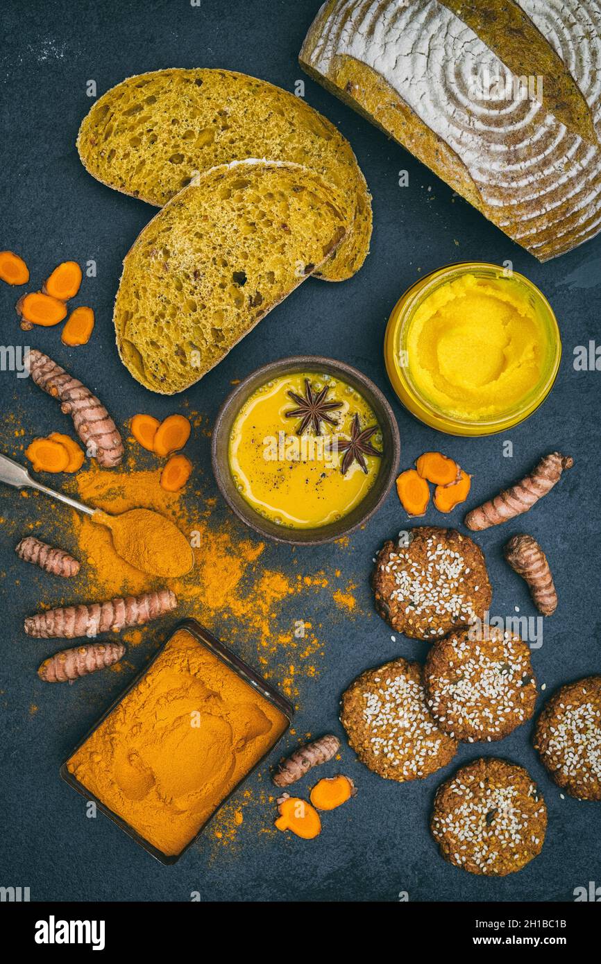 Turmeric golden milk, powder, root, ghee, bread and biscuits on a slate background Stock Photo