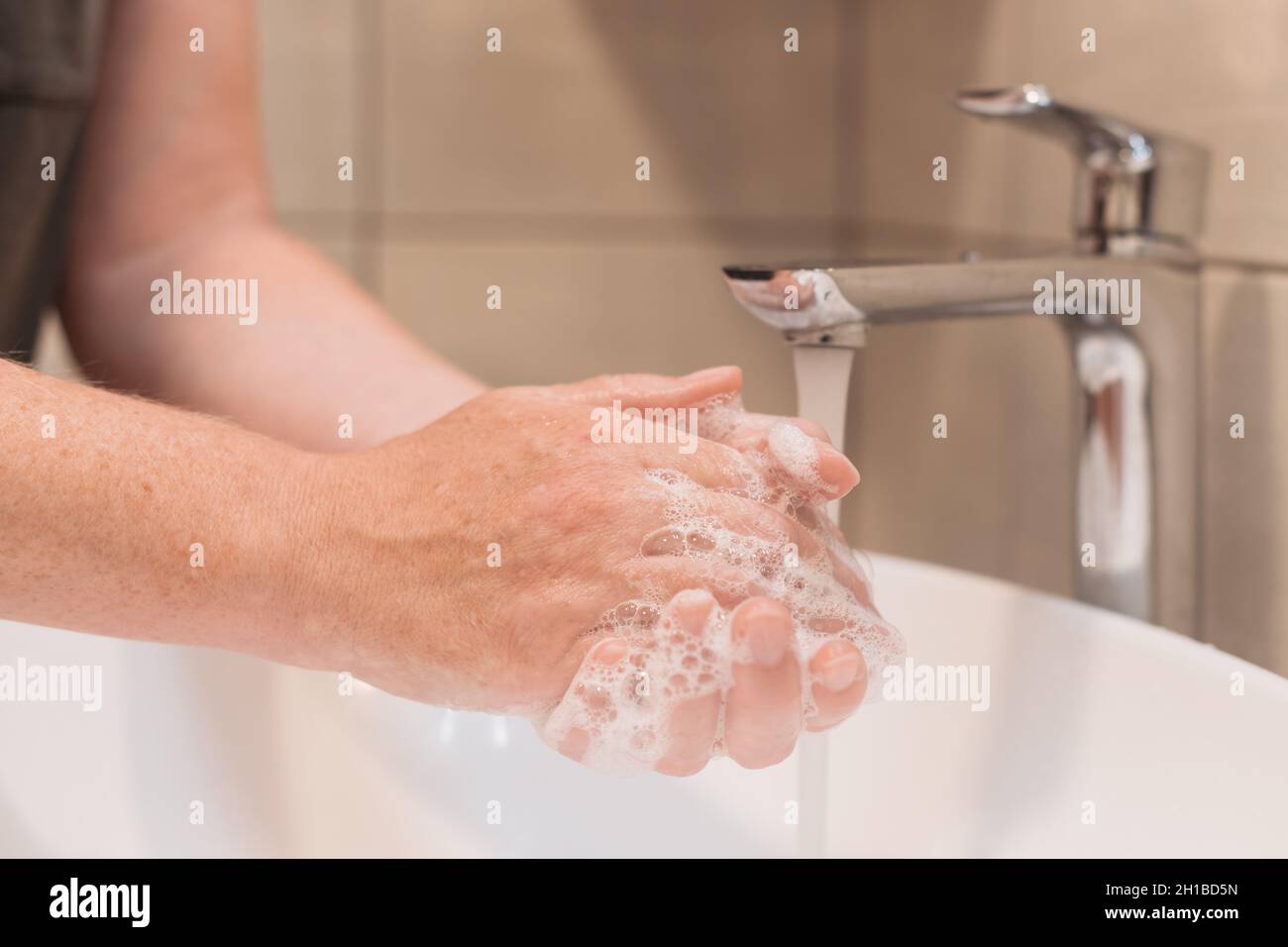 Close up of female washing hands with soap in bathroom, selective focus Stock Photo