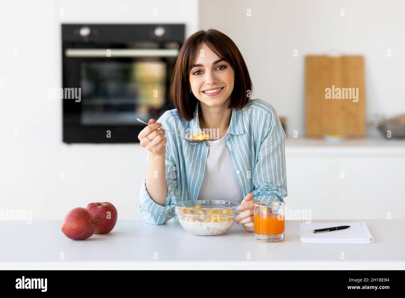 Healthy breakfast concept. Happy lady eating muesli bowl with apples