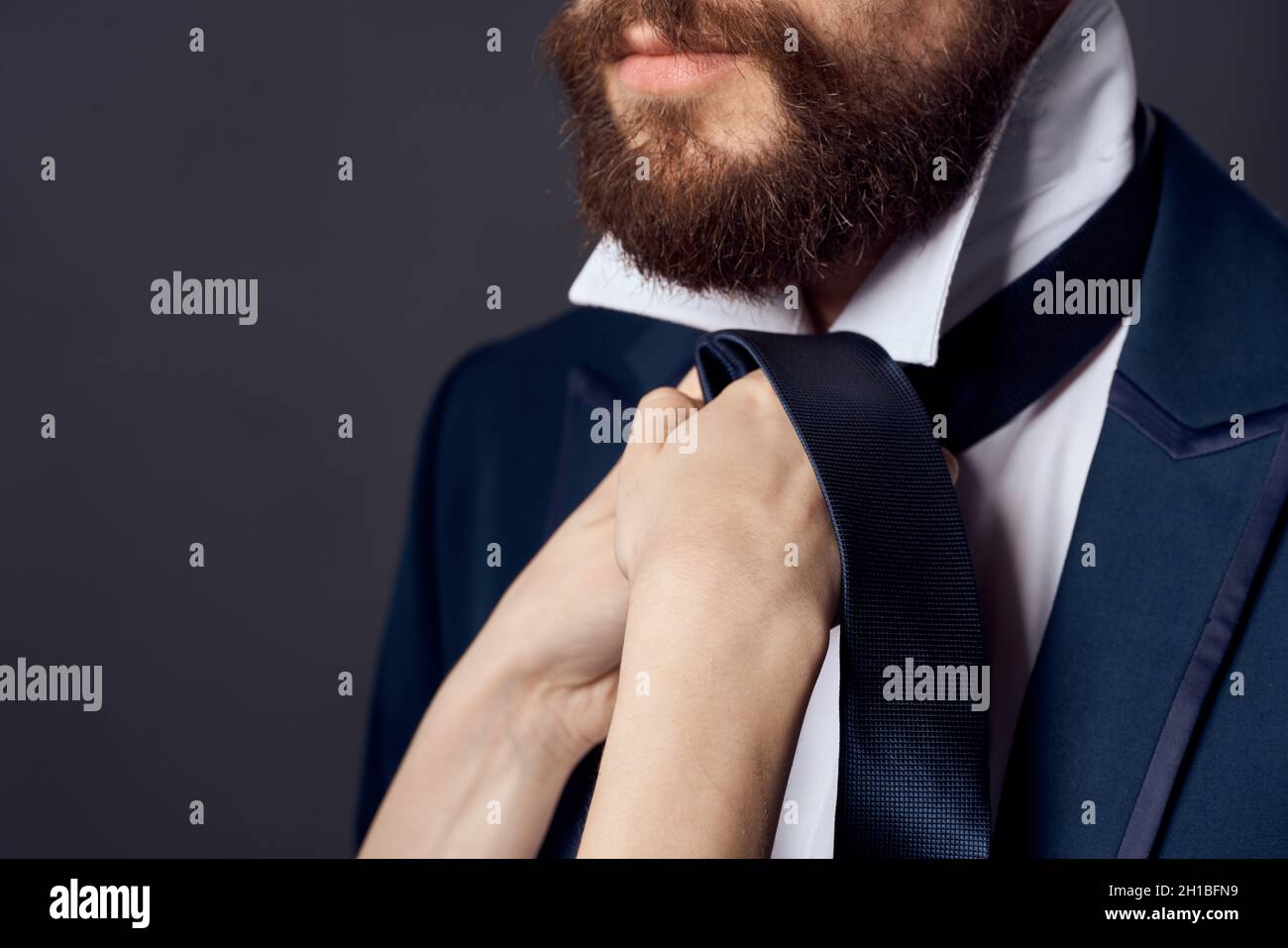 man in suit tying tie elegant style dark background Stock Photo - Alamy