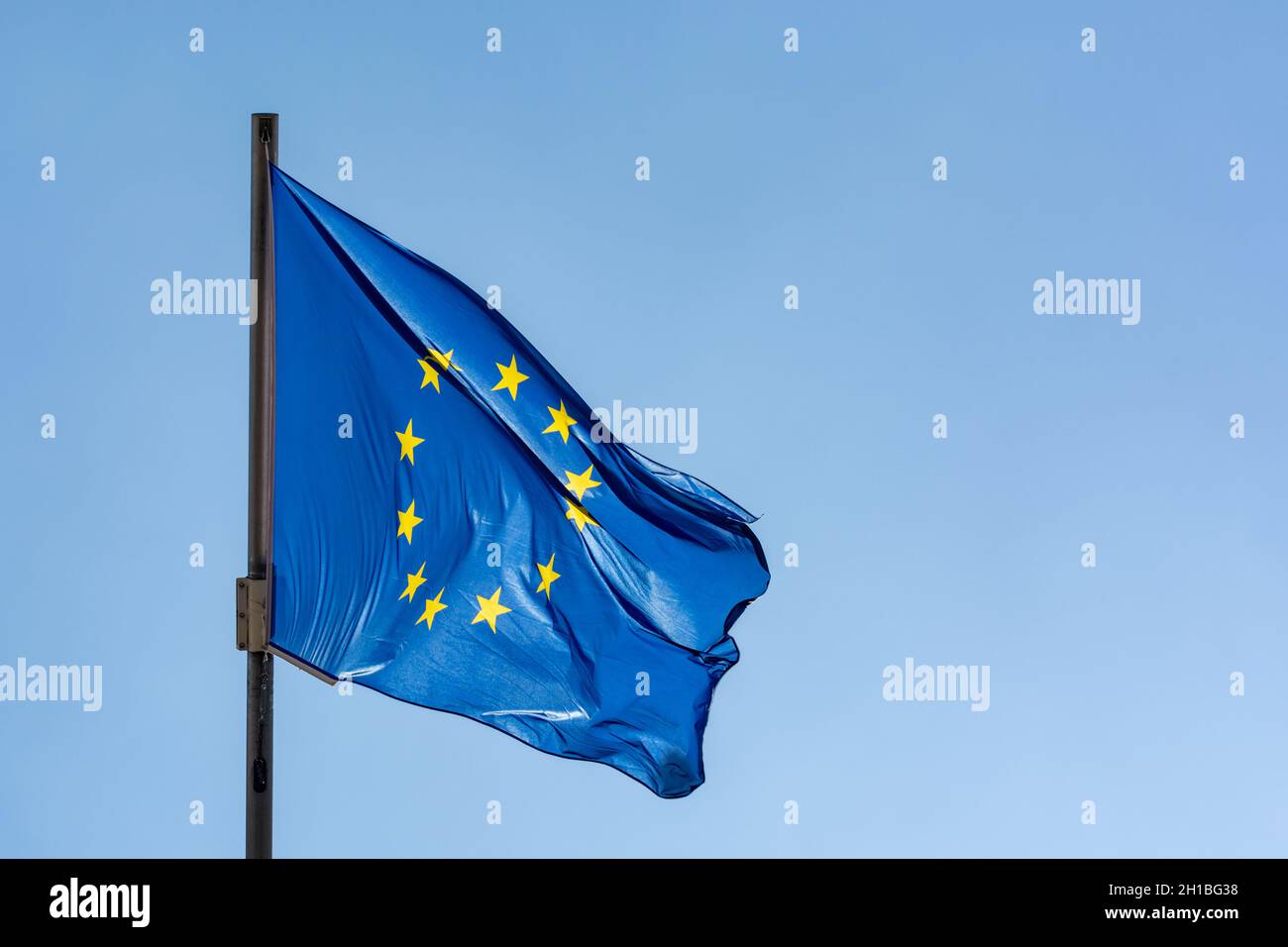Blue with yellow stars flag of European Union waving on flagpole and ...