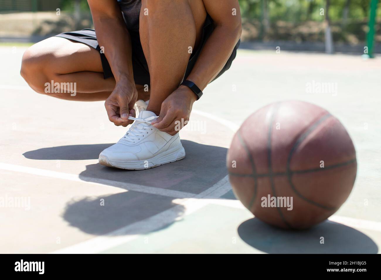 Mature man tying his shoelaces on the basketball court Stock Photo Alamy