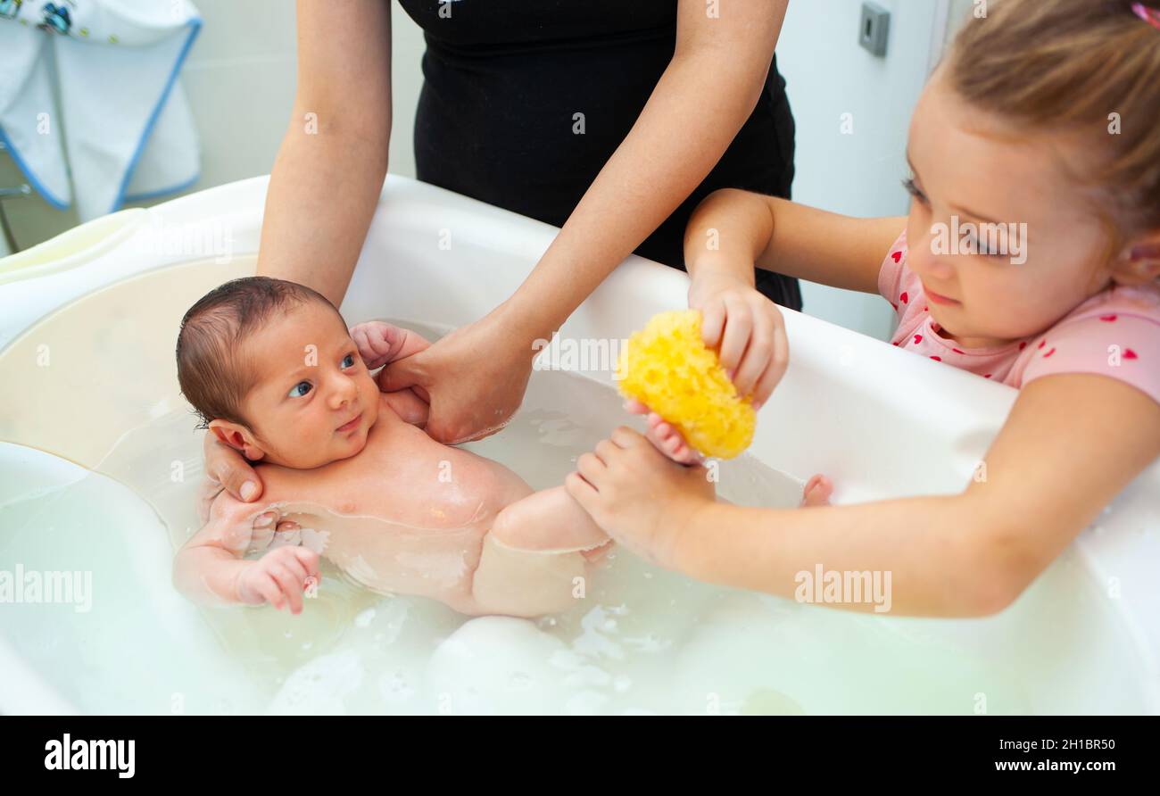 First bath of newborn baby boy.The mom washes the baby with natural sponge. Stock Photo