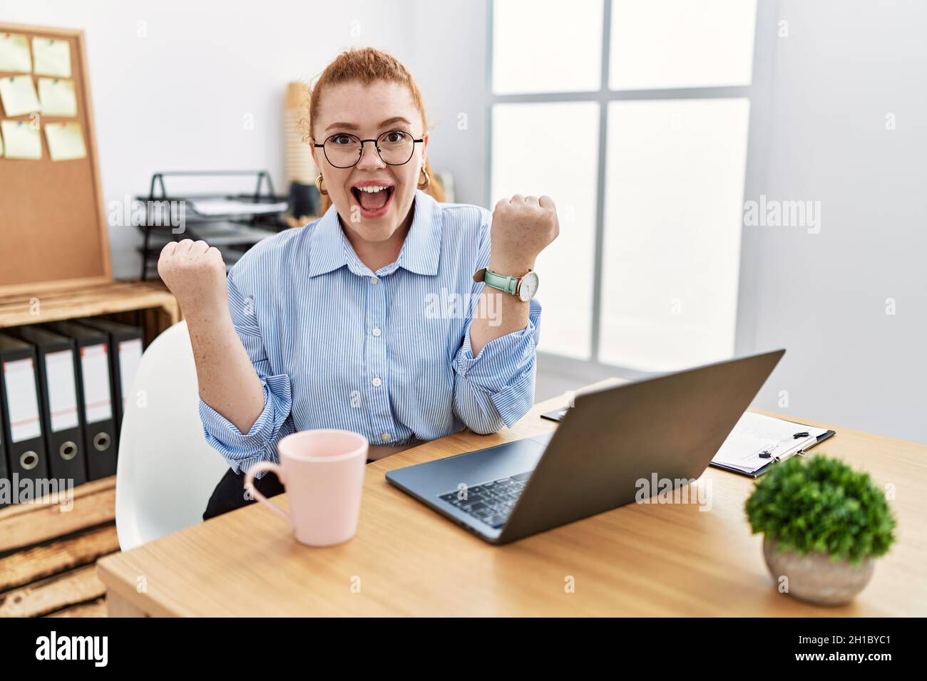 Young redhead woman working at the office using computer laptop very ...