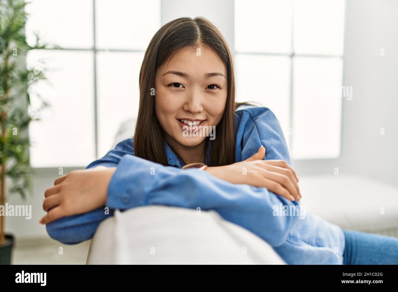Young chinese girl smiling happy sitting on the sofa at home Stock ...