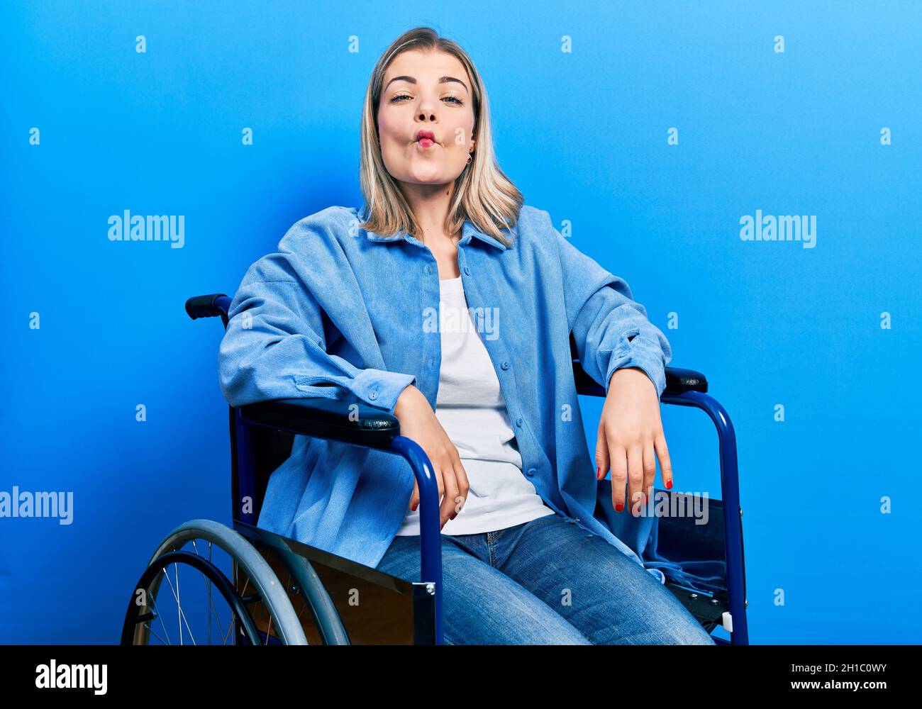 Beautiful caucasian woman sitting on wheelchair making fish face with lips,  crazy and comical gesture. funny expression Stock Photo - Alamy