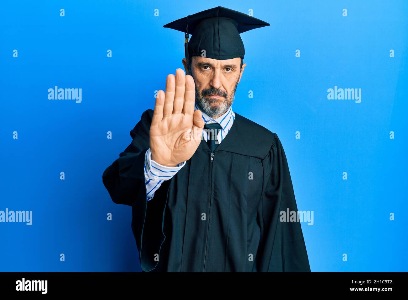 Middle age hispanic man wearing graduation cap and ceremony robe doing ...