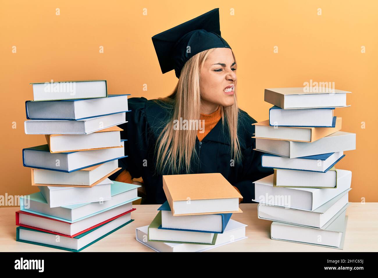 Young caucasian woman wearing graduation ceremony robe sitting on the ...