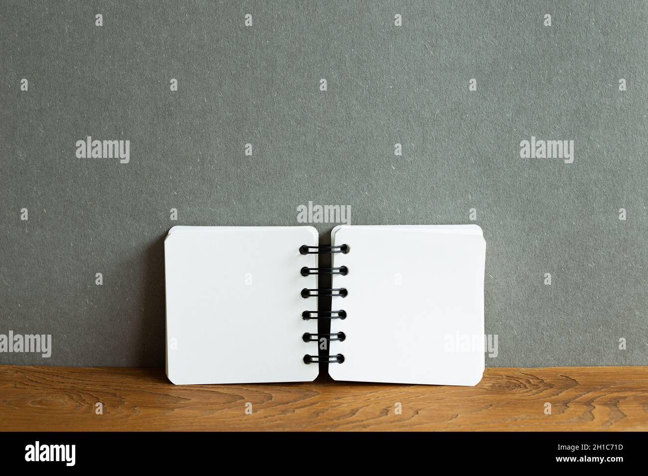 Blank notebook on wooden desk. gray wall background Stock Photo