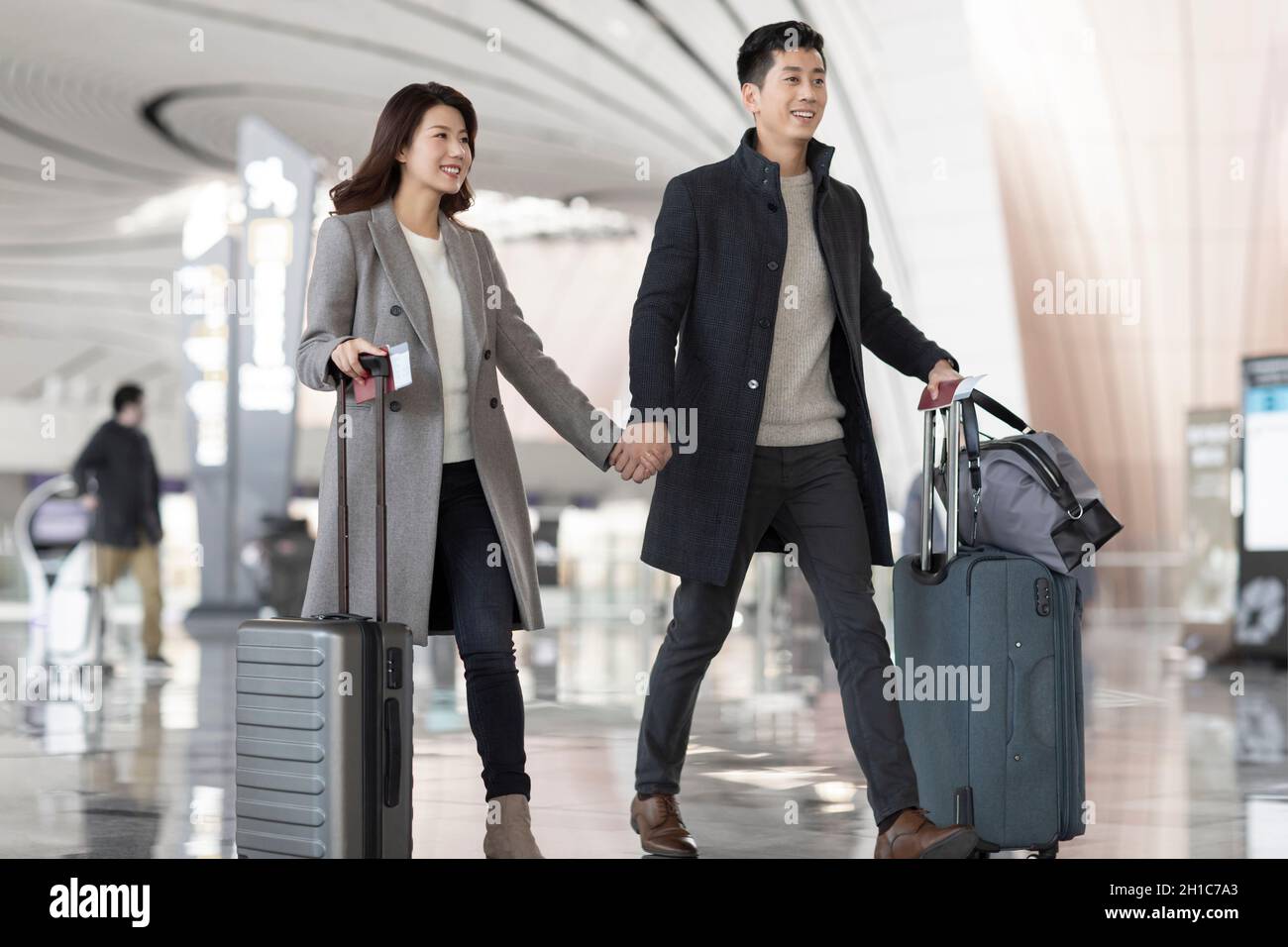 Happy young couple holding hands at the airport Stock Photo - Alamy