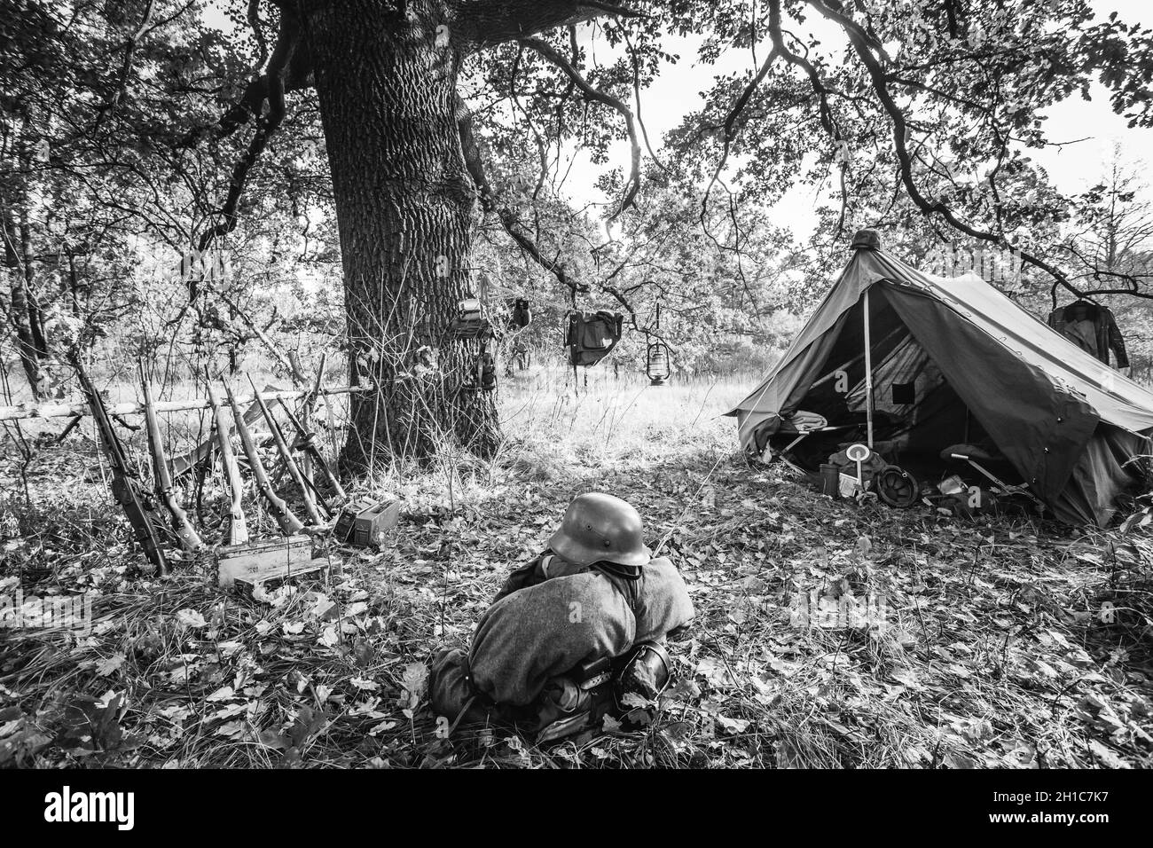 World War II German Wehrmacht Infantry Soldier Army Weapon Ammunition. Helmet, Rifles, Tent In Forest Camp. WWII WW2 German Ammunition. Photo In Black Stock Photo