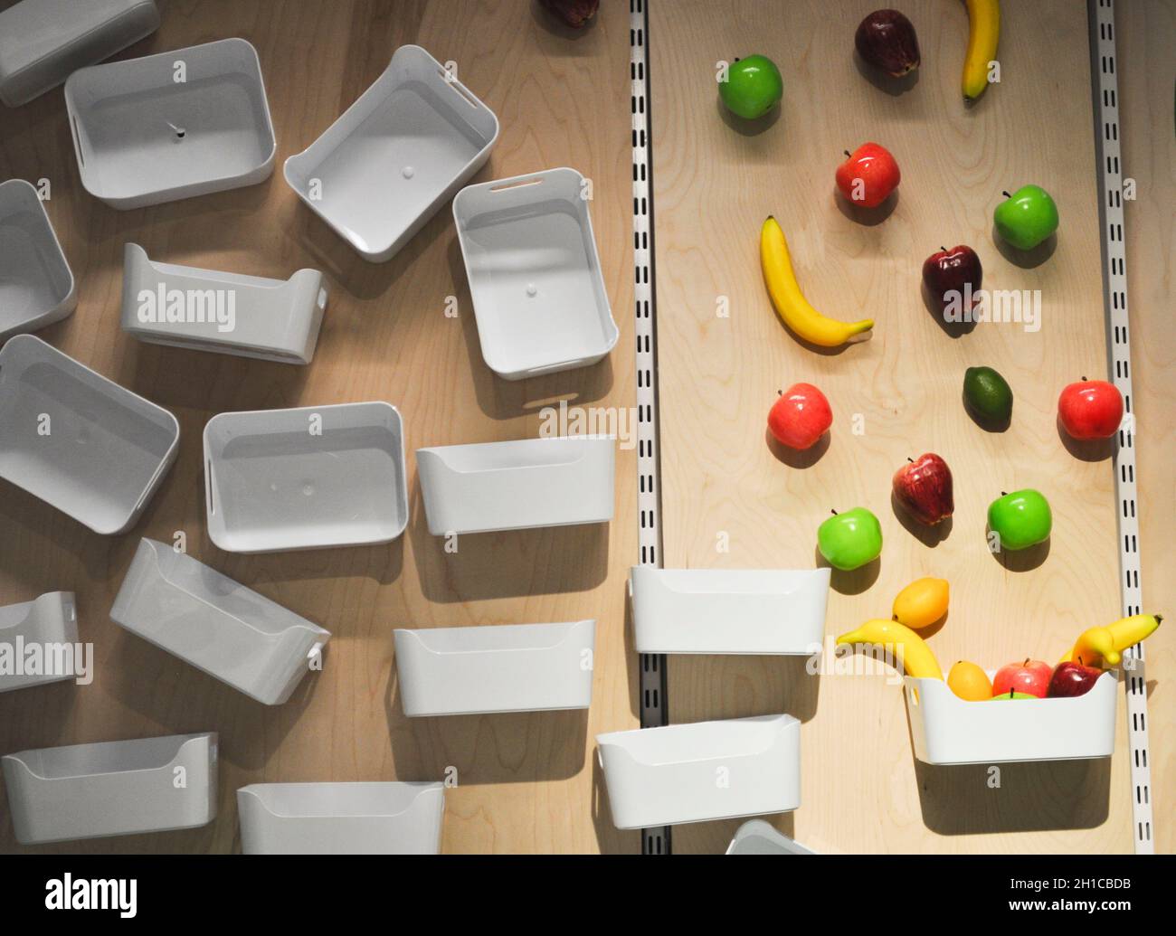 Plastic storage trays with carry handles and plastic fruit on a wall