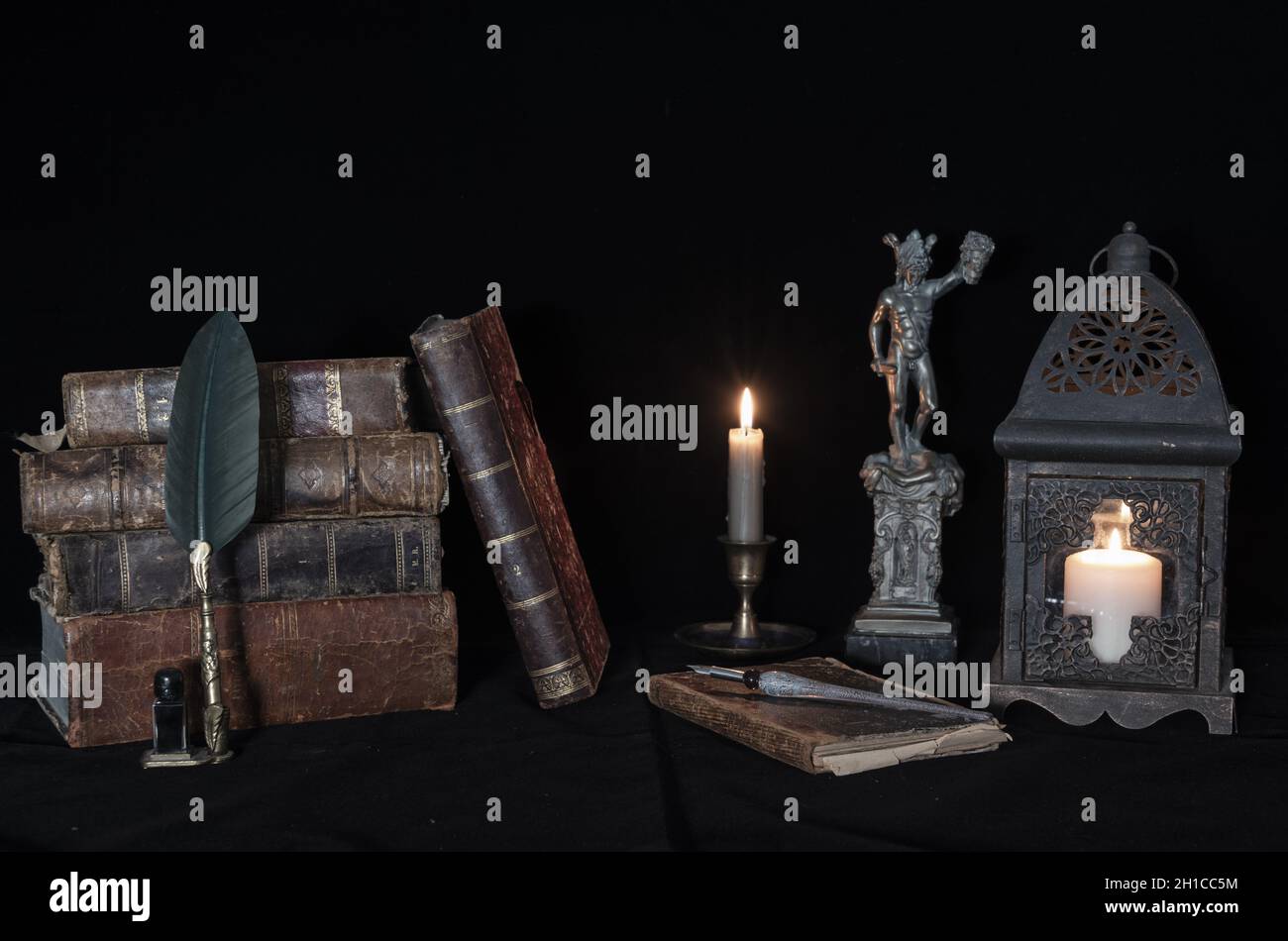 medusa statue next to antique books and candlelight. Stock Photo