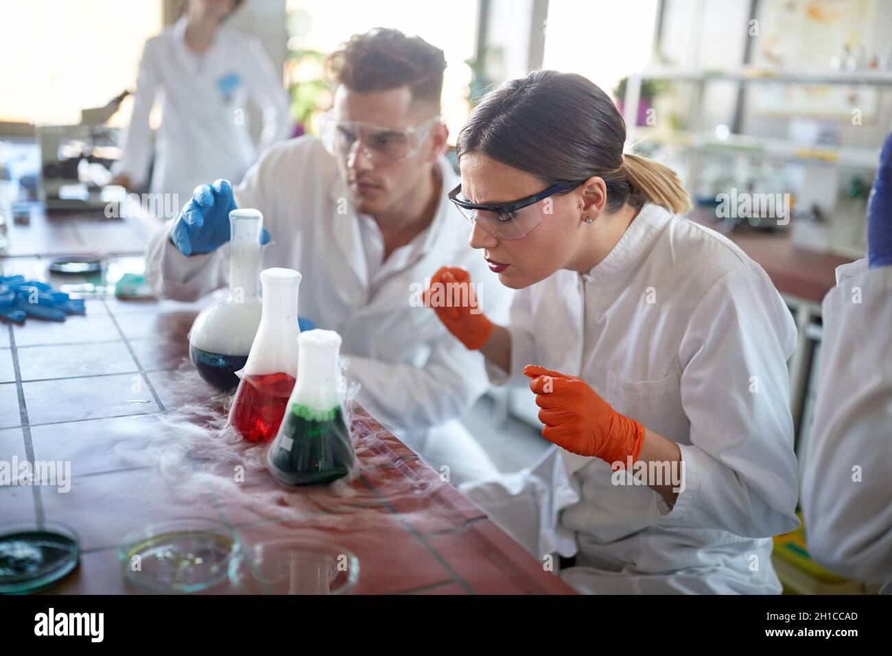 Laboratory workers looking chemical reaction in glassware Stock Photo