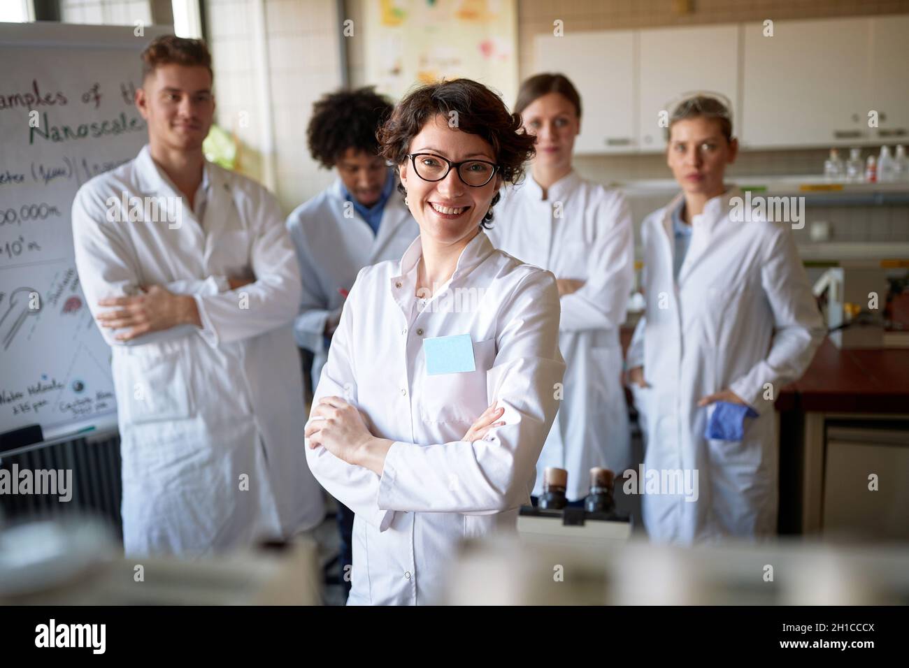 Pretty smiling female with colleagues in lab Stock Photo