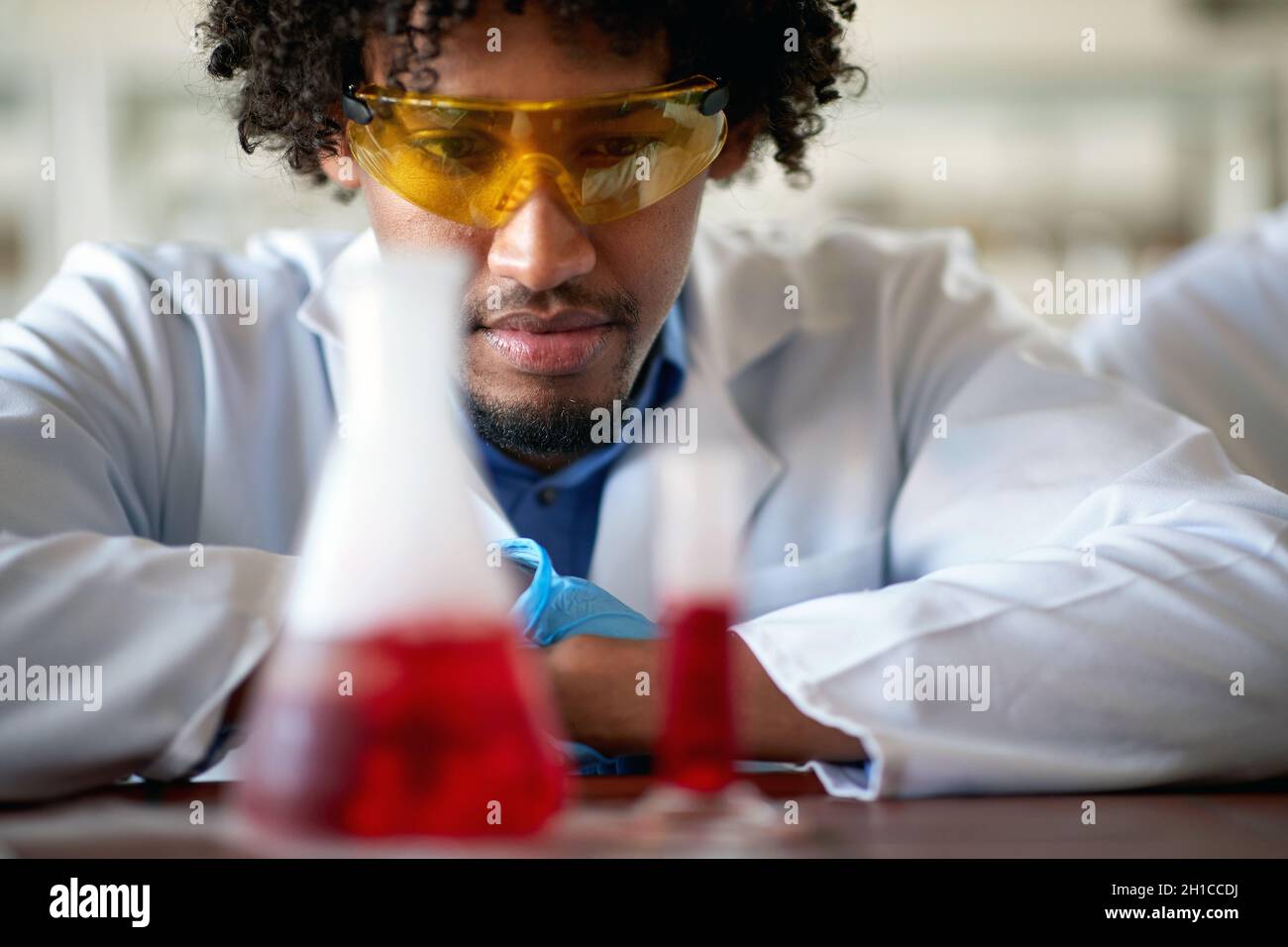 A young male chemistry student observes a chemical in a test tube in a relaxed atmosphere in the laboratory. Science, chemistry, lab, people Stock Photo