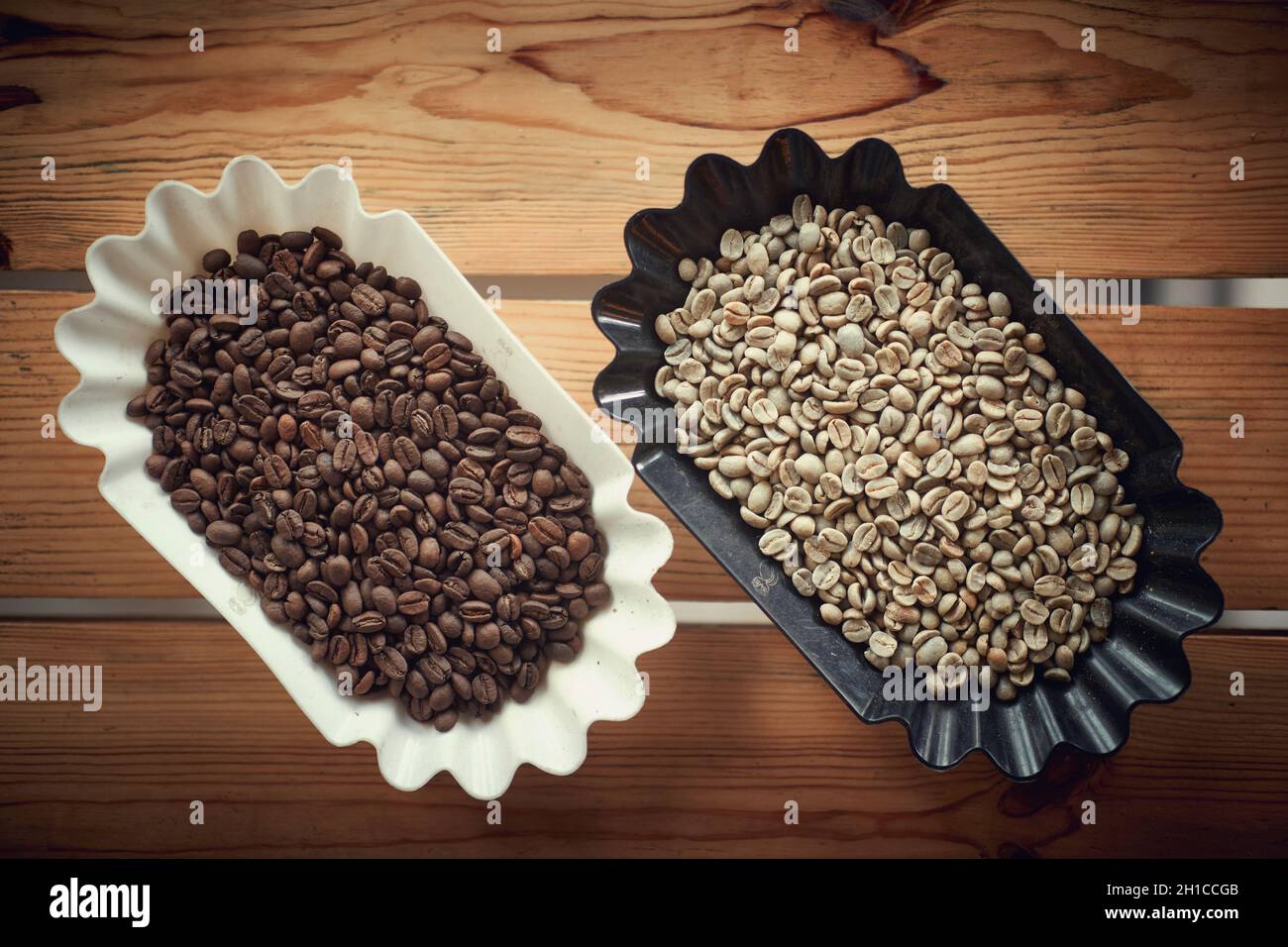 Fragrant and aromatic raw and roasted coffee beans in containers on the table. Coffee, beverage, producing Stock Photo