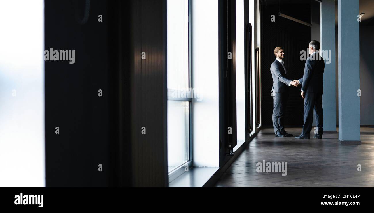 Full length view of businessmen shaking hands in office building Stock ...