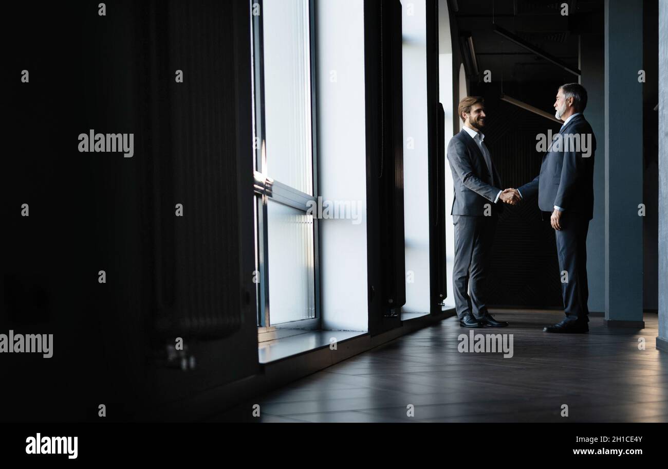 Full length view of businessmen shaking hands in office building Stock ...